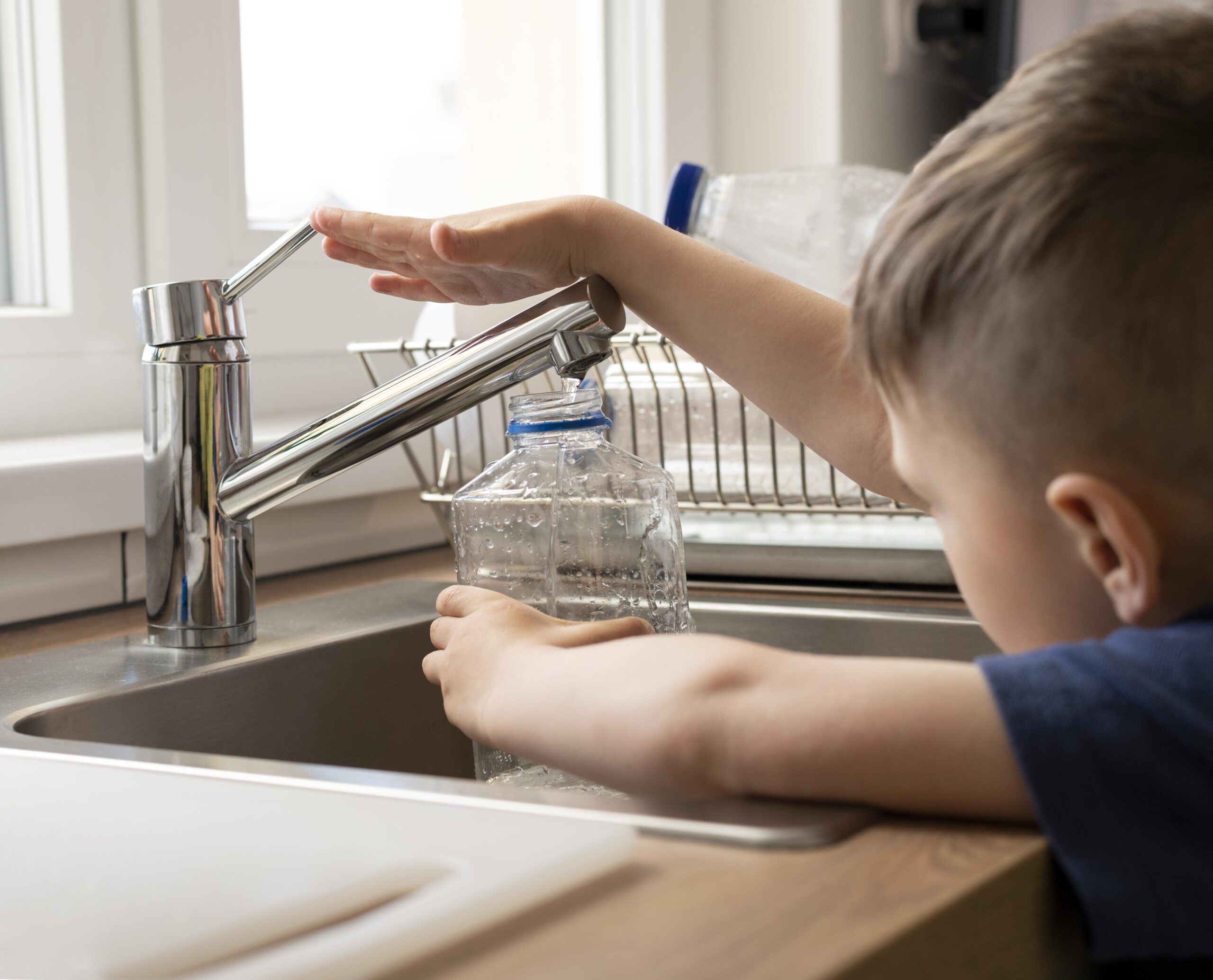 close up kid filling bottle with water scaled